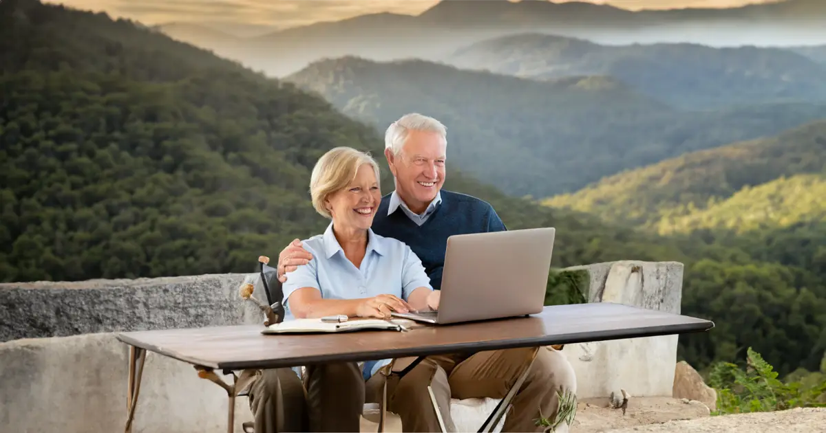 A couple sitting together surrounded but mountains happily planning their retirement