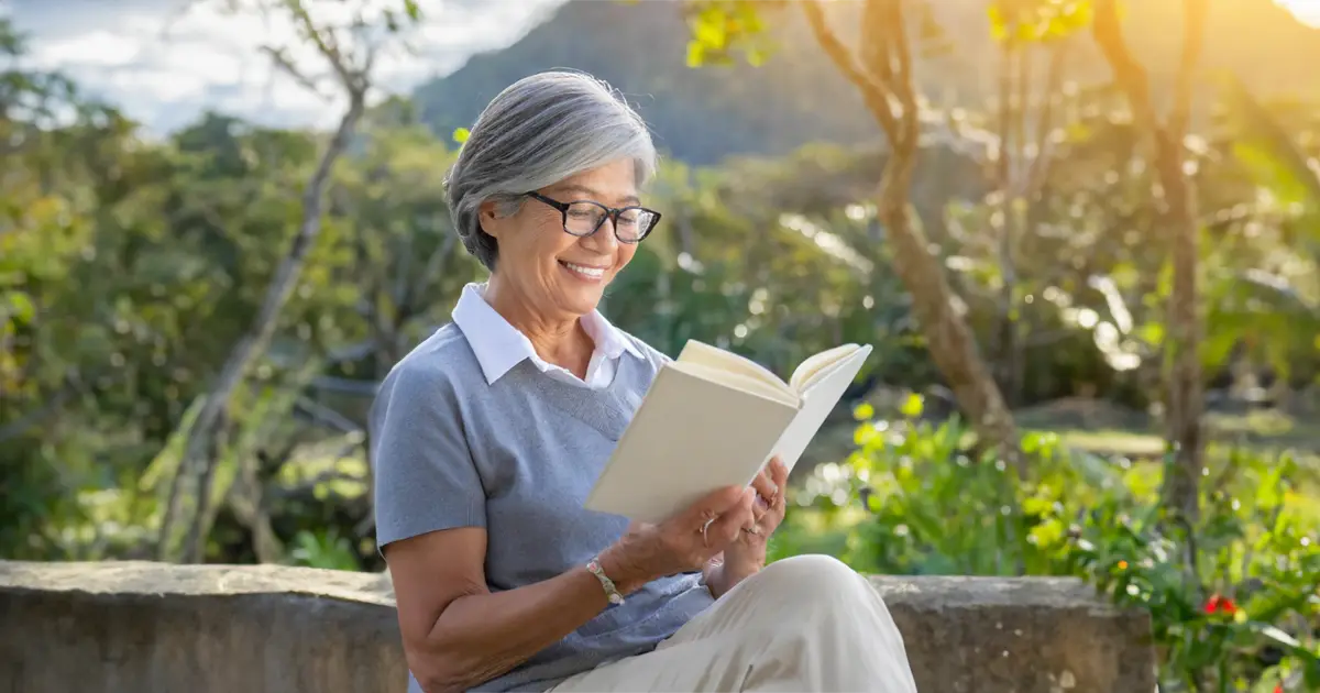 A senior woman reading a book and setting her retirement goals