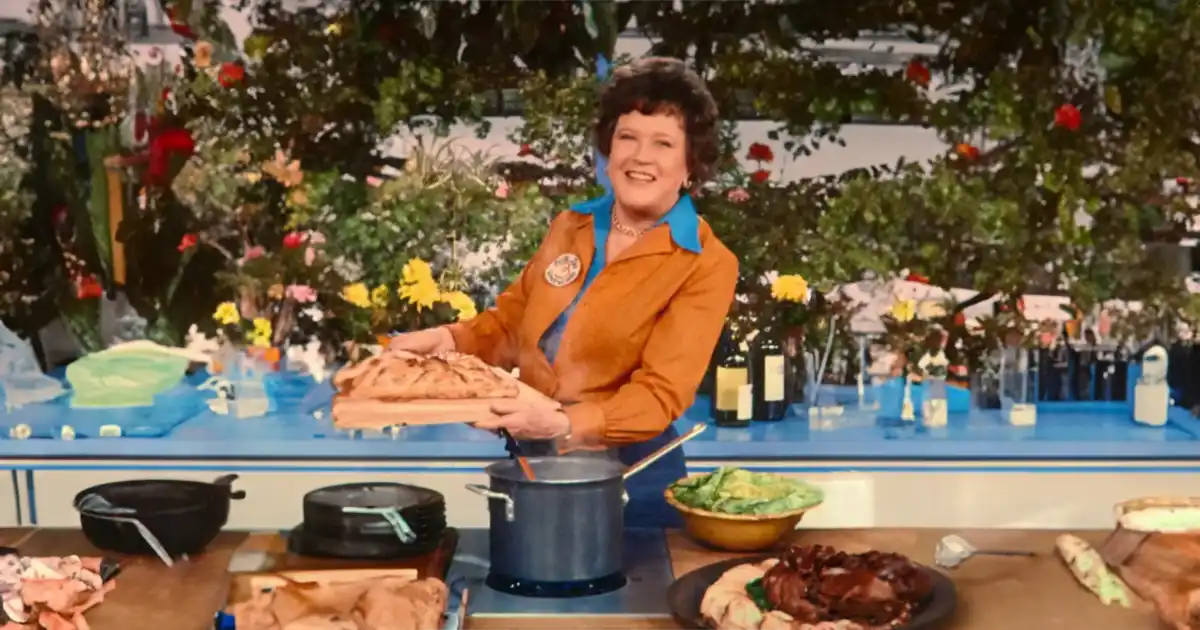 Chef Julia Child in her kitchen holding a tray of baked goods