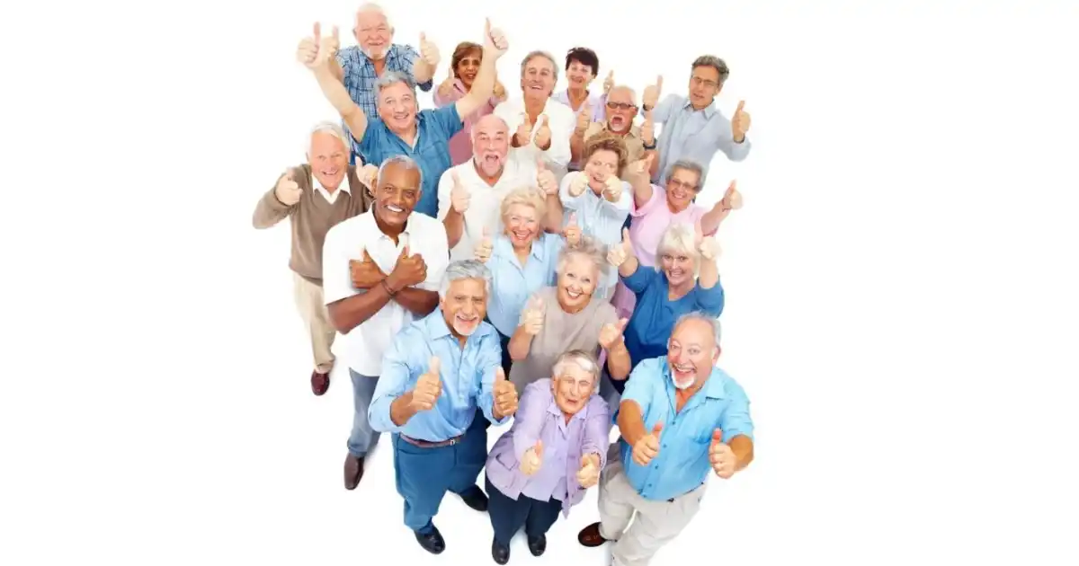 A group of mature men and women looking up and smiling with thumbs up