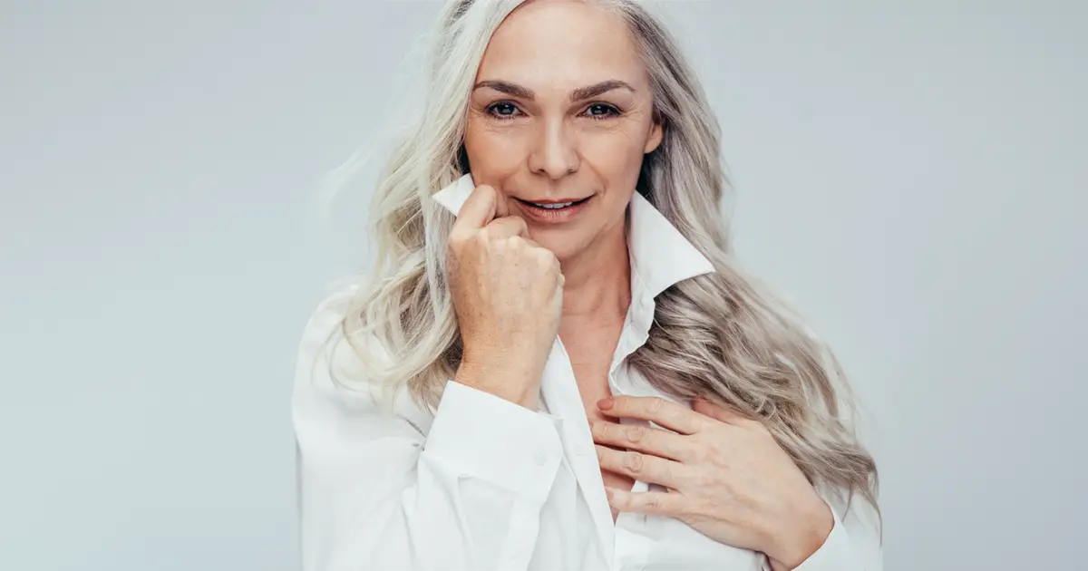 Woman with long grey hair wearing a white shirt