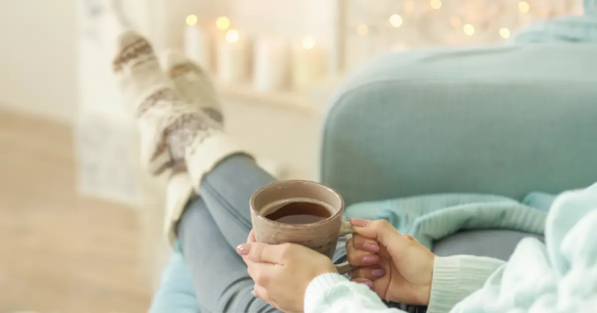 A woman sitting in her chair with her feet up, enjoying a cup of coffee