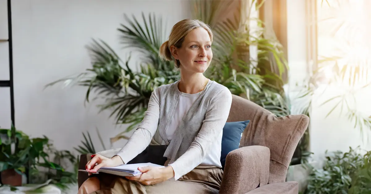 A woman with grey-blonde hair in therapy looking out the window while feeling content