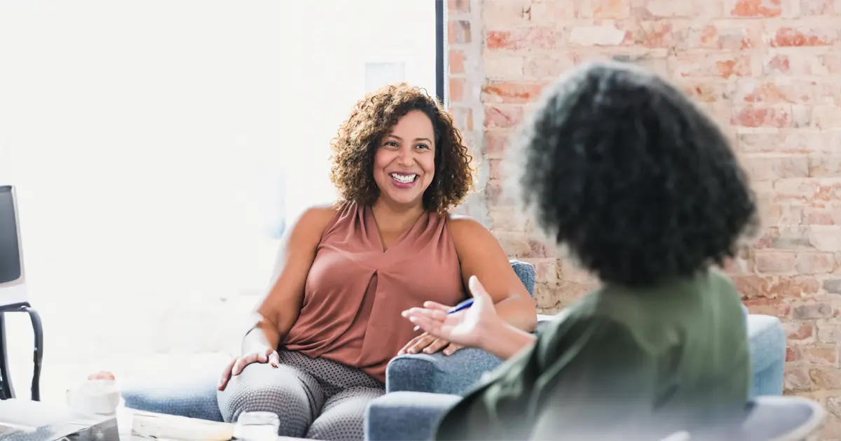 A woman with brown curly hair listening to her therapist while feeling at peace