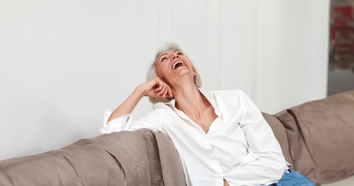 Woman sitting on the couch throwing her head back laughing