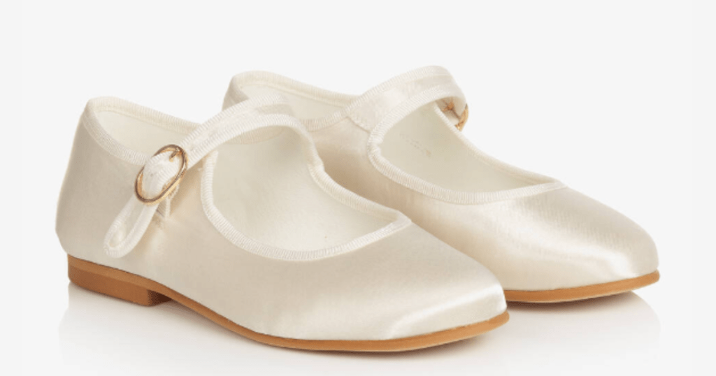 A white satin pair of a child’s size Mary-Jane shoes