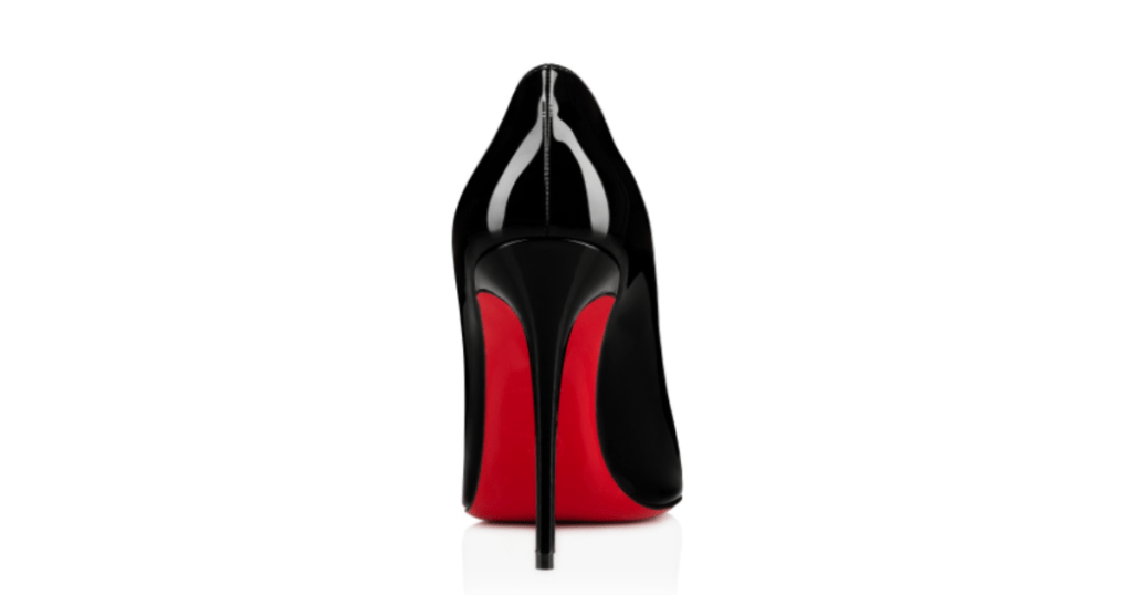 A single black Louboutin patent leather high heeled shoe with a red sole.