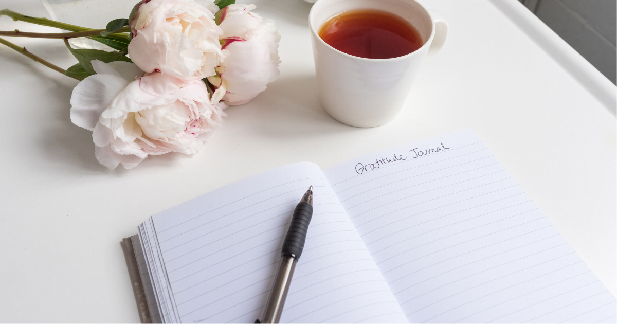 A gratitude journal that’s laid out with a pen, ready for the owner to write in it.