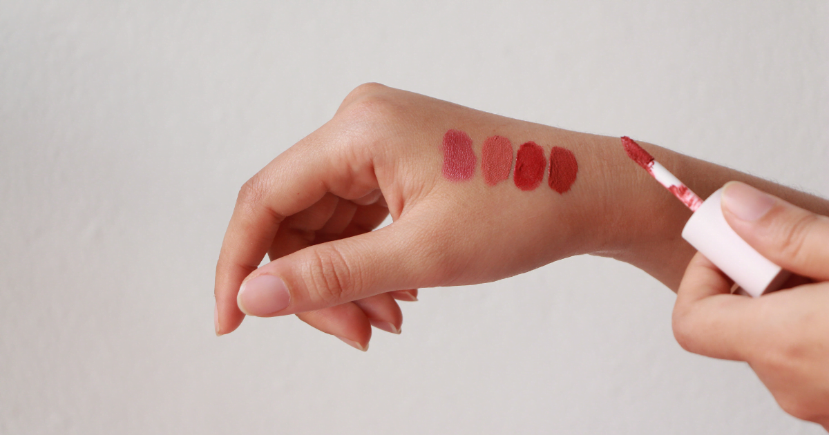 A woman's hand with four different lipstick colours on it.