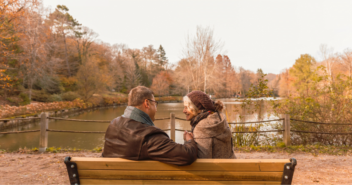 An older couple going on a date at a park smiling and having fun