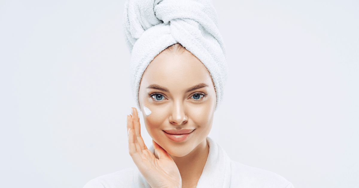 A heavily airbrushed and edited photo of a smiling younger woman in a bathrobe with her hair wrapped in a white towel. 