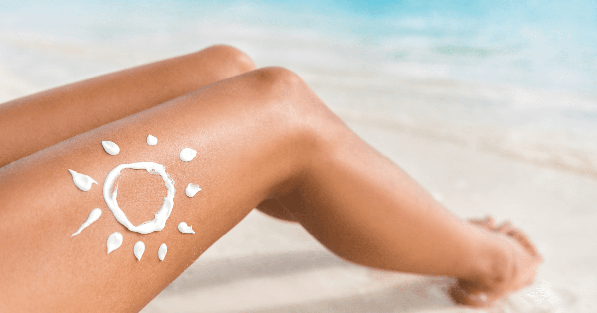 Woman’s bare legs with a sun symbol made with sunscreen