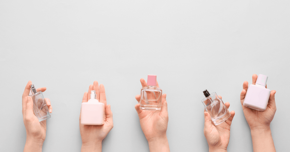 Women’s hands holding a variety of perfume bottles and creams.